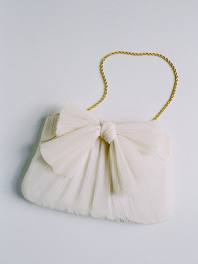 A white bow clutch with a gold chain on a grey background.