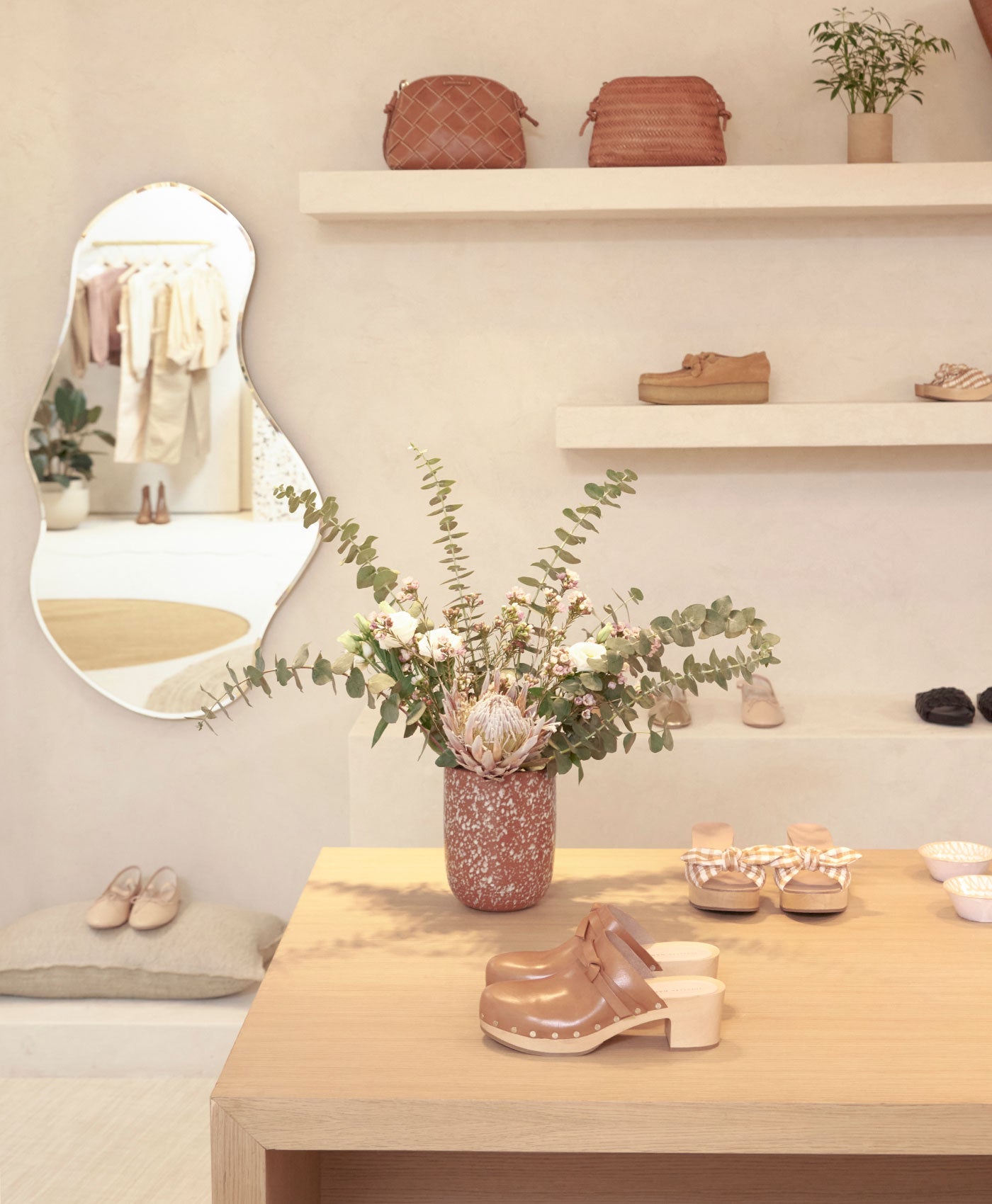 A photo of a display table with flowers and shoes displayed in a brightly lit store.