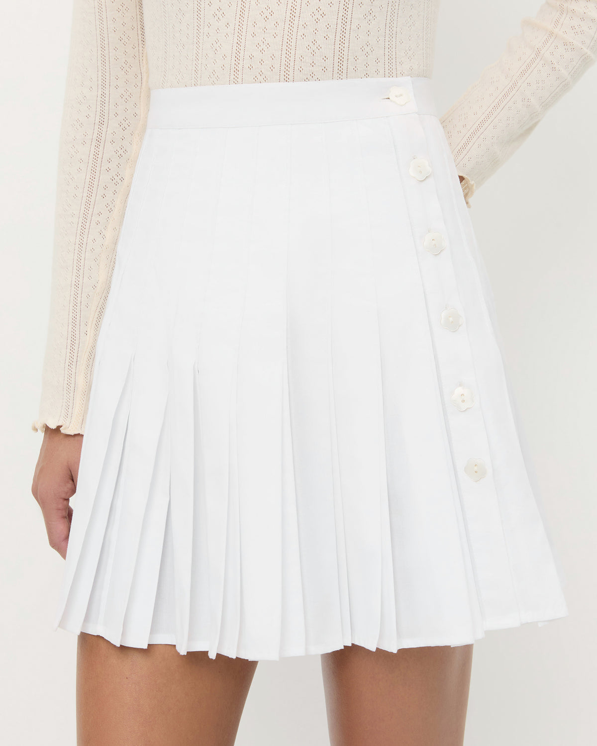 Caroline Mini Skirt in white cotton and Lolo Pointelle Long Sleeve Top in cream cotton.