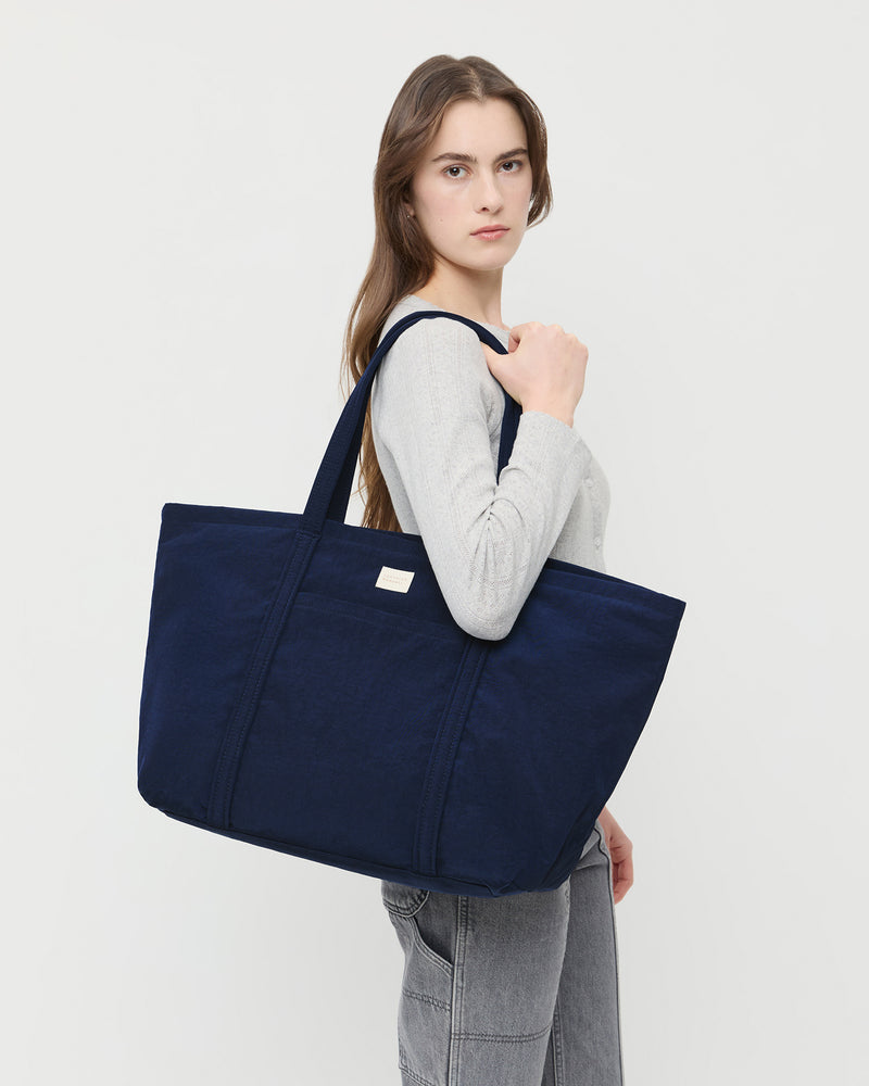 Dina Navy Travel Tote in navy nylon, Lolo Pointelle Long-Sleeve Tee in grey cotton, and Molly Workwear Jean in grey denim.
