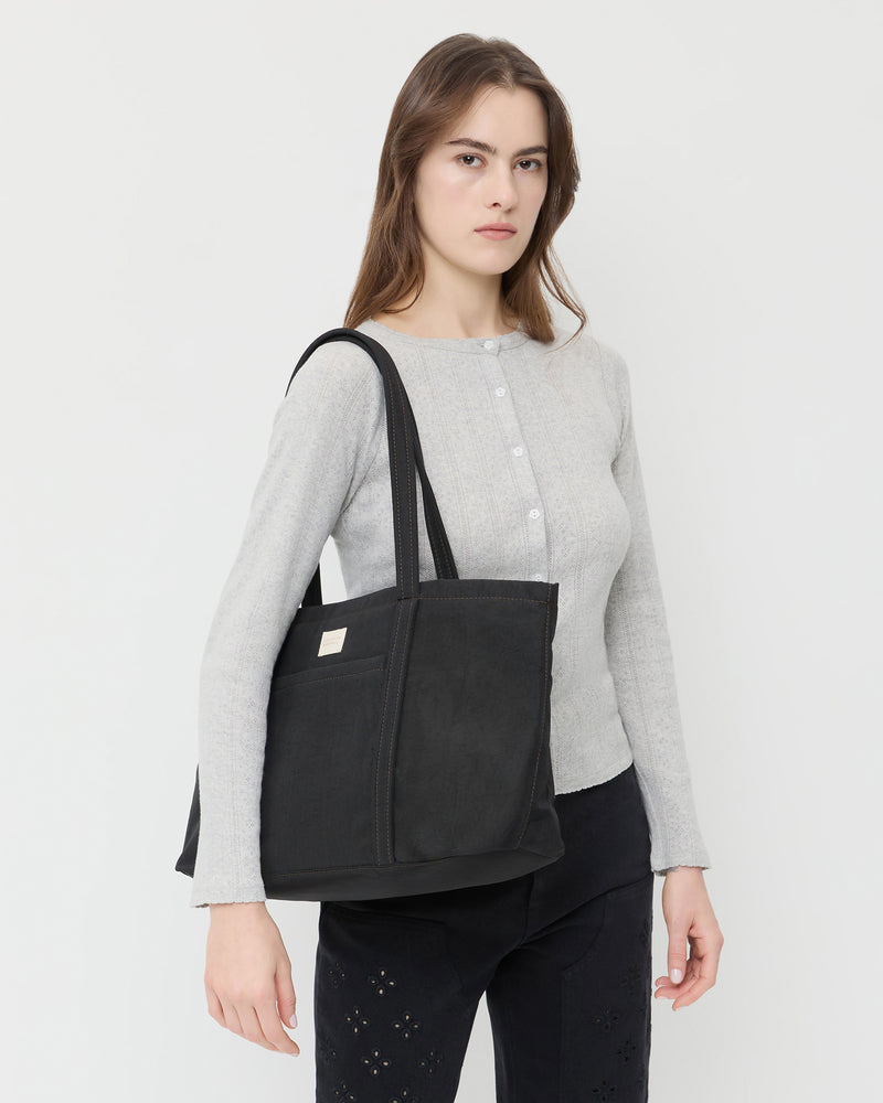 Mira Black Everyday Tote Bag in water-resistant nylon, Ash Pointelle Cardigan in grey cotton, and Demi Embroidered Pant in black denim.