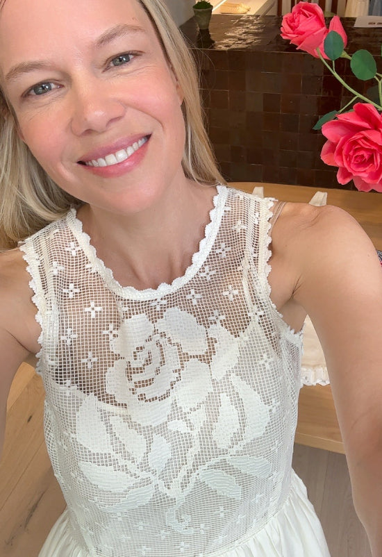 Jessie takes a selfie wearing a white lace dress that has the print of a rose in it's detail.