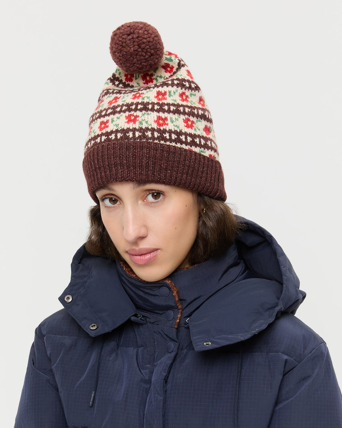 Macelyn Brown Floral Intarsia Hat in brown floral intarsia wool and Pippa Puffer Coat in navy nylon.