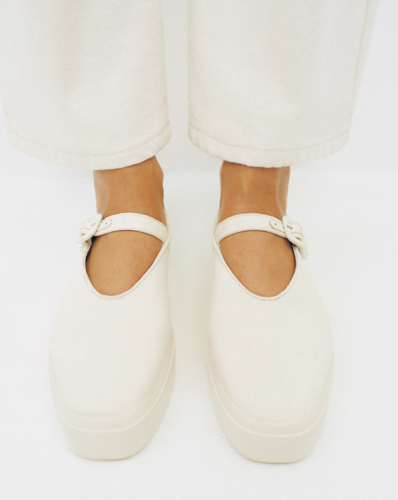 An overhead view of a pair of white mary jane sneakers on a white background.