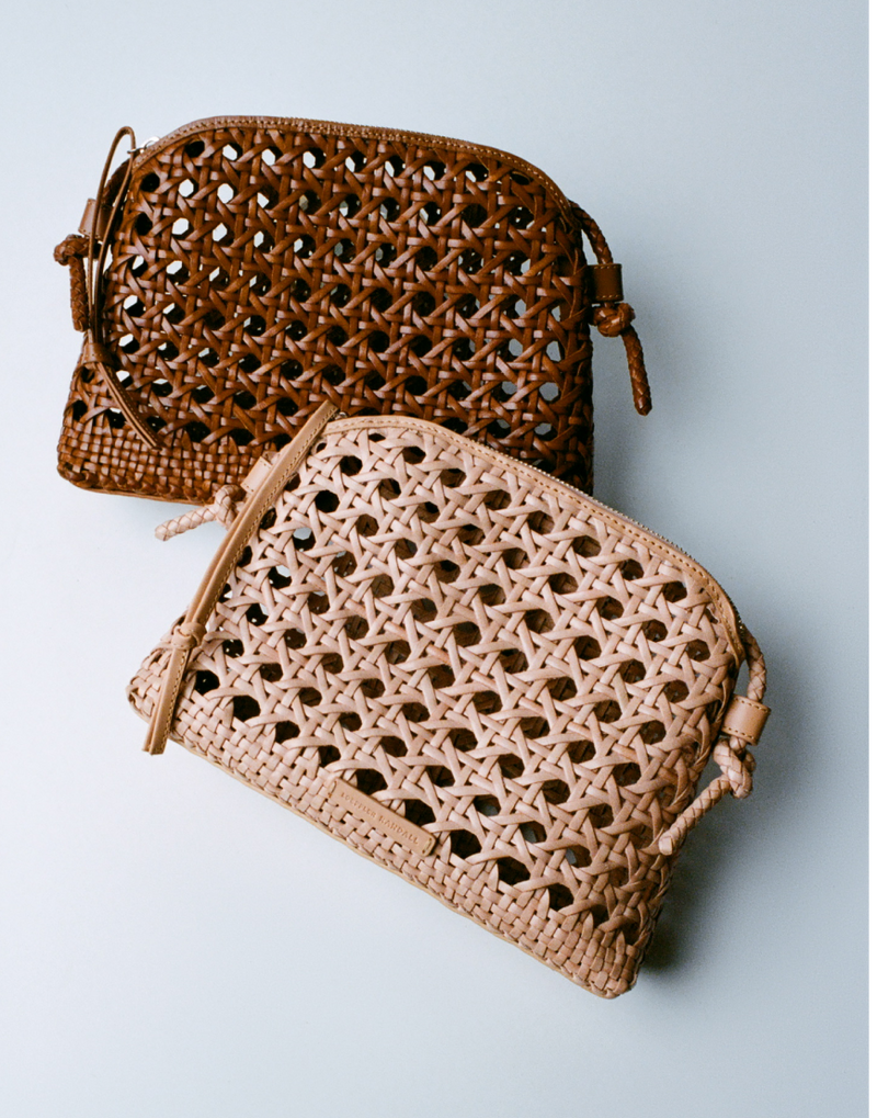 Two open weave leather crossbodies leaned against one another on a grey background. 