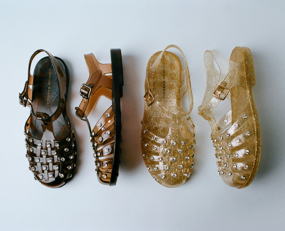 An overhead view of two pairs of jelly sandals, one in brown and one in champagne each with one shoe turned on its side on a grey background.